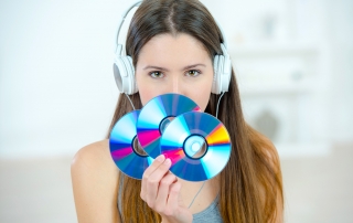 Lady with headphones holding three CDs